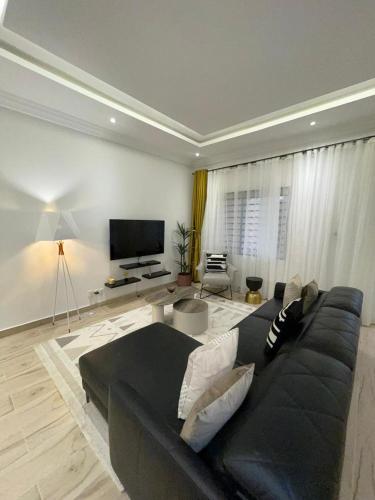 a living room with a black couch and a flat screen tv at Résidence Daniel in Pointe-Noire