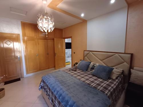 Un dormitorio con una cama y una lámpara de araña. en Belle vacances dans mon App, en Meknès