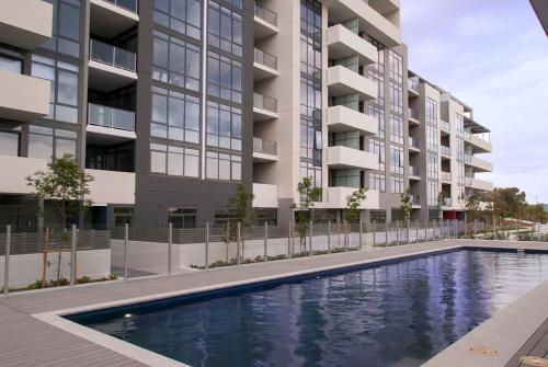 an image of an apartment building with a swimming pool at Modern 1 Bedroom apartment with Pool, Gym & Water Views in Belconnen