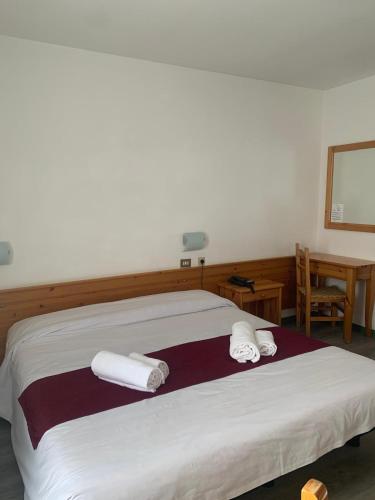 a bedroom with a bed with towels on it at Hotel Fraiteve in Cesana Torinese