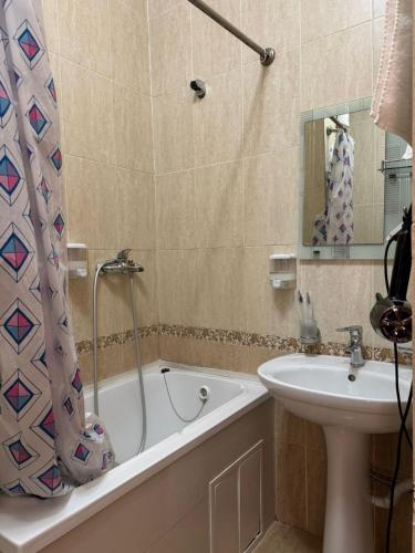 a bathroom with a tub and a sink and a shower curtain at Belon Life Hotel in Astana
