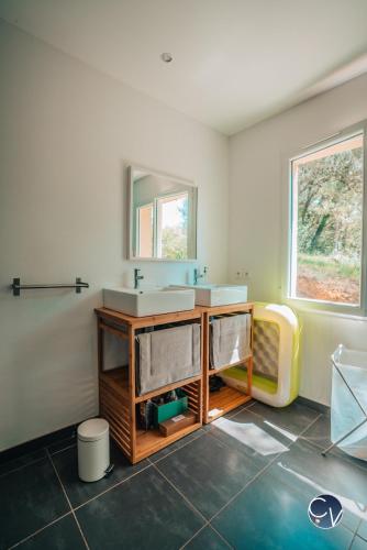 une salle de bain avec deux lavabos et un miroir dans l'établissement La Marjelle, Havre de paix en pleine nature avec piscine, à Montclus
