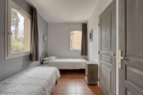 Cette chambre comprend 2 lits, une porte et une fenêtre. dans l'établissement Bellevue 4 pers - Les issambres - piscine - vue mer, à Roquebrune-sur Argens