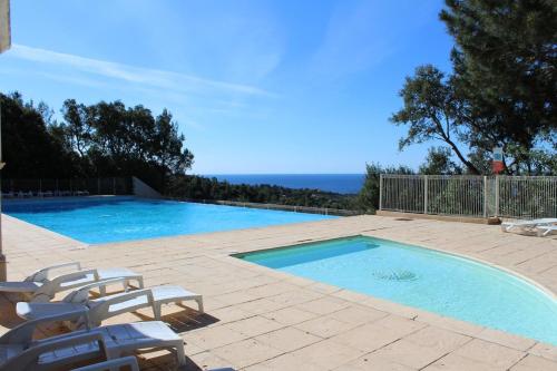 une piscine avec des chaises et l'océan en arrière-plan dans l'établissement Bellevue 4 pers - Les issambres - piscine - vue mer, à Roquebrune-sur Argens