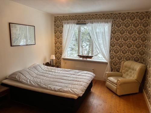 a bedroom with a bed and a chair and a window at Urlaub auf dem Hergard Västra Tönnet in Ekshärad