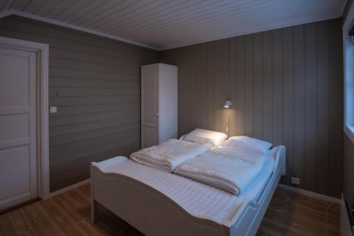 a bed with white sheets and pillows in a room at Bakkebyvegen 15B in Trysil