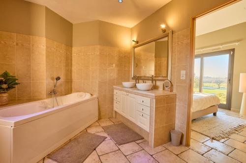Un baño con bañera, lavabo y espejo. en Villa du Monde - 160 m² avec piscine privée, en Saint-Rémy