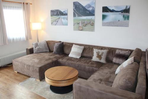 un salon avec un canapé marron et une table dans l'établissement Ferienhaus Nr 22, Kategorie Komfort Plus L, Feriendorf Hochbergle, Allgäu, à Karlsebene