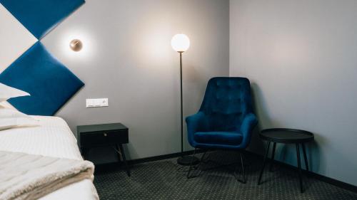 a room with a bed and a blue chair and a lamp at Centrum Hotel Viljandi in Viljandi