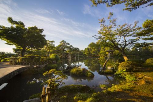 a garden with a pond and trees and a bridge at Tokyu Stay Kanazawa in Kanazawa