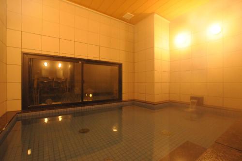 una piscina in una camera piastrellata con finestra di AB Hotel Tahara a Tahara