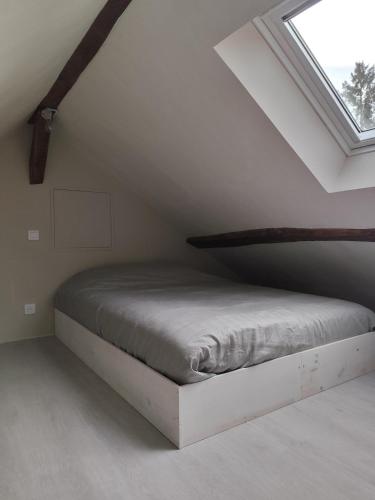 Ce lit se trouve dans une chambre mansardée dotée d'une fenêtre. dans l'établissement Studio avec mezzanine, à Mamers