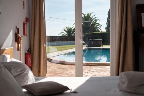 a bedroom with a view of a swimming pool through a door at A Casa Branca - with Pool & Jacuzzi in Santa Comba Dão