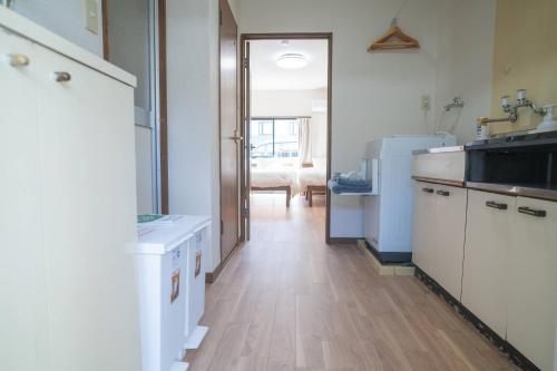 a kitchen with white cabinets and a wooden floor at Seeds Stay Ijiri in Fukuoka
