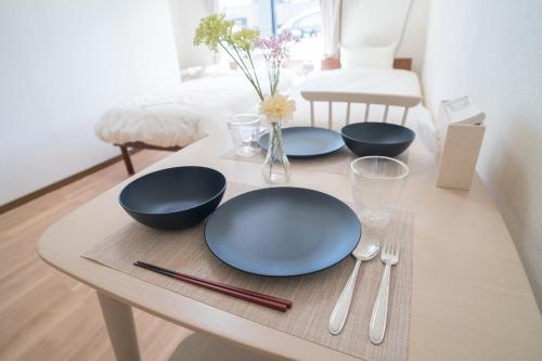 a table with blue plates and utensils on it at Seeds Stay Ijiri in Fukuoka