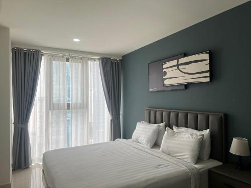 a bedroom with a bed with white sheets and a window at The PeAk Residence, Multi-Apartment by Emma in Phnom Penh
