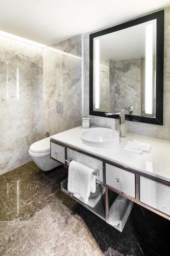 a bathroom with a sink and a toilet and a mirror at The Marmara Taksim in Istanbul