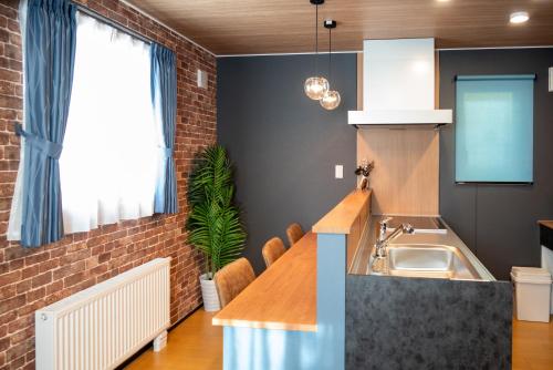 a kitchen with a sink and a brick wall at Rocky-F in Furano