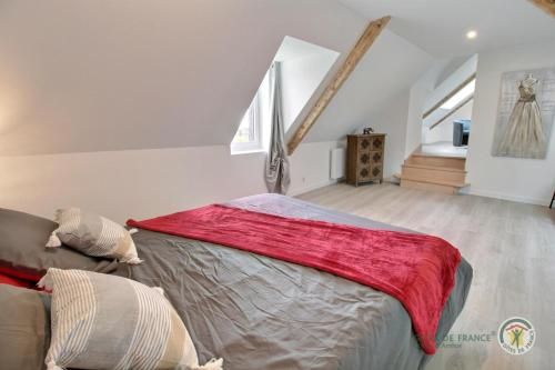 a bedroom with a large bed with a red blanket at La forge de la fontaine in Pléhédel