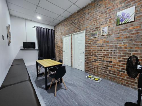 a room with a brick wall and a table and chairs at Tamu 1980 Studio in Kampong Molek