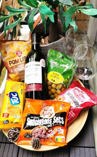 a plate of food with a bottle of wine and snacks at Reims Appart - Idéal pour Pro en déplacement *Wifi rapide *Vue panoramique *Parking facile in Roubaix