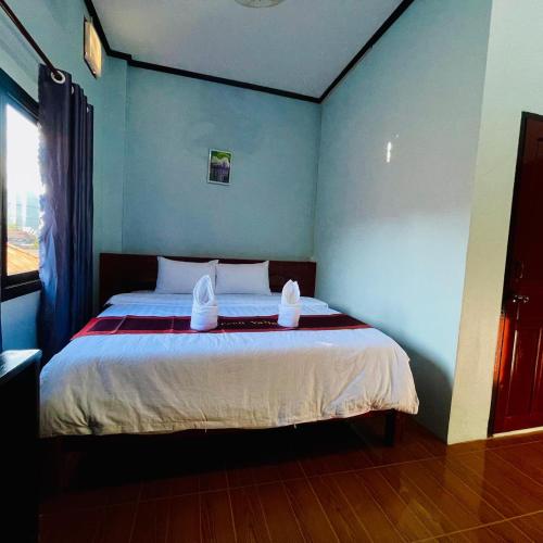 a bedroom with a bed with two towels on it at Smile Guesthouse VangVieng in Vang Vieng