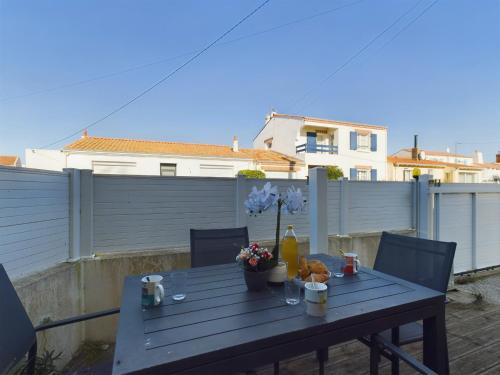 d'un balcon avec une table en bois et des fleurs. dans l'établissement Appartement pour 4 avec balcon et terrasse, à Les Sables-dʼOlonne