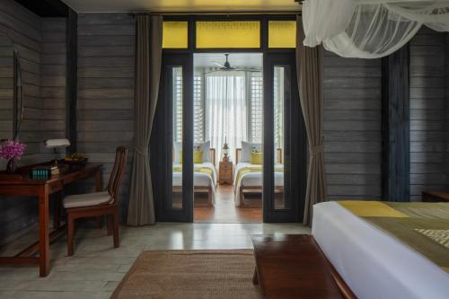 a bedroom with a bed and a desk and a room at Anantara Lawana Koh Samui Resort in Chaweng