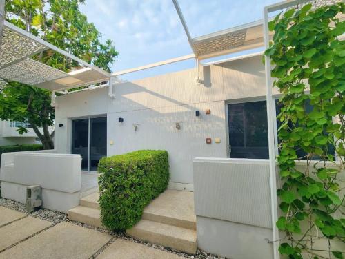 a white house with stairs and a green bush at BBG Beachfront poolvilla 5BR close to Huahin city in Cha Am