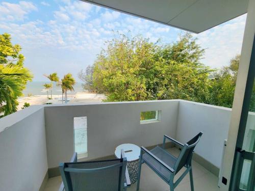 a balcony with a table and chairs and a view of the beach at BBG Beachfront poolvilla 5BR close to Huahin city in Cha Am