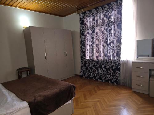 a bedroom with a bed and a dresser and a window at Hotel Cattaleya in Batumi
