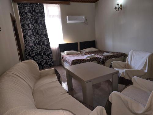 a room with three beds and a table and chairs at Hotel Cattaleya in Batumi