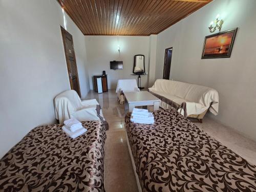 a room with a bed and a couch and a table at Hotel Cattaleya in Batumi