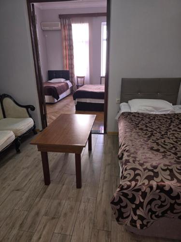 a bedroom with a bed and a table and a couch at Hotel Cattaleya in Batumi