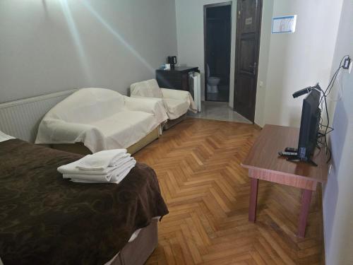 a room with two beds and a table and a television at Hotel Cattaleya in Batumi