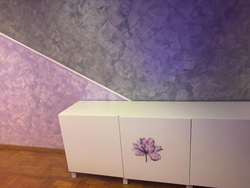 a white cabinet with a flower painted on it next to a purple wall at Michelle Luxury Living in centro a Gorizia in Gorizia