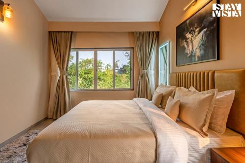 Un dormitorio con una cama grande con ventana. en StayVista at Casa Elyra with Pool, AC, Balcony, en Lonavala