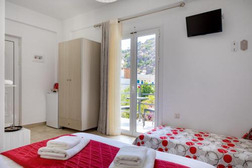 a bedroom with two beds and a sliding glass door at John Akroyiali in Loutro