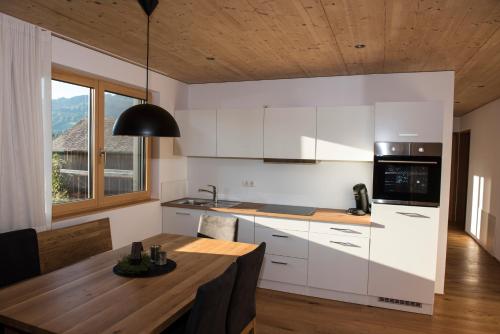 a kitchen with white cabinets and a wooden table at Ferienwohnung R45 in Andelsbuch