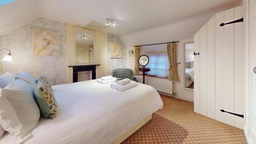 ein Schlafzimmer mit einem großen weißen Bett und einem Kamin in der Unterkunft Hannah Cottage in Adderbury
