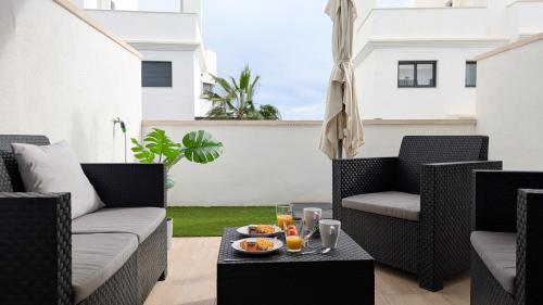 eine Terrasse mit Korbstühlen und einem Tisch mit Getränken in der Unterkunft PANORAMIC relax apartment in Finestrat