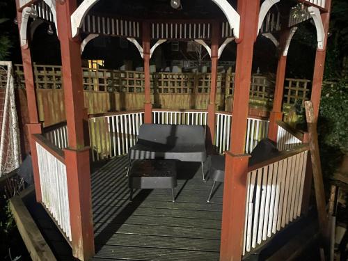 a wooden gazebo with a table and a chair at Vancouver Place in Orpington