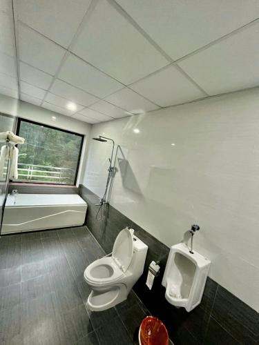 a bathroom with a toilet and a bath tub and a urinal at Phong Nha Moonlight Villas in Phong Nha