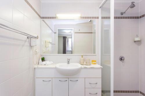 a white bathroom with a sink and a mirror at Resort-style living in Perth CBD - 2X2 Apt in Perth