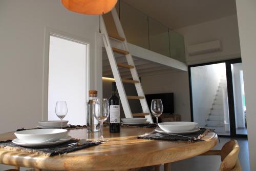 a wooden table with plates and glasses and a ladder at Casa Amoreira in Carrapateira