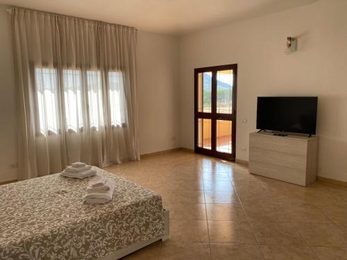 a bedroom with a bed and a television and a door at Bellavista in Castiadas