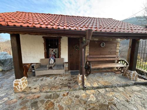 a small house with a porch and a dog in the doorway at Къща За Гости Двата Ореха in Protopopintsi
