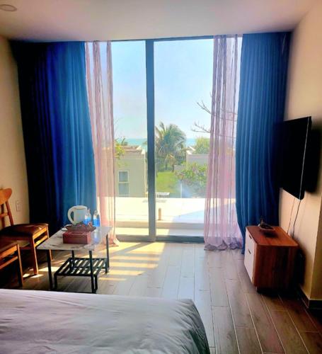 a bedroom with a bed and a large sliding glass door at Beach Oceanami Villa in Long Hai