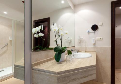 a bathroom with a sink and a vase with white flowers at Impressive Playa Granada Golf in Motril