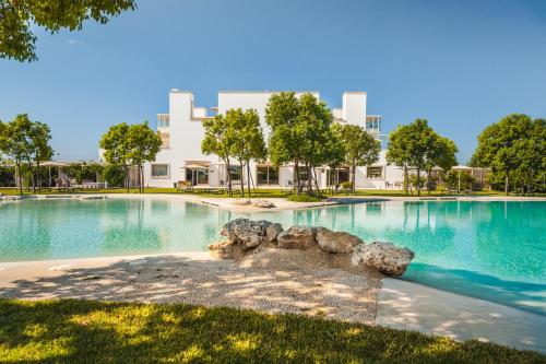 una gran piscina con árboles y edificios en el fondo en Furnirussi Tenuta, en Carpignano Salentino